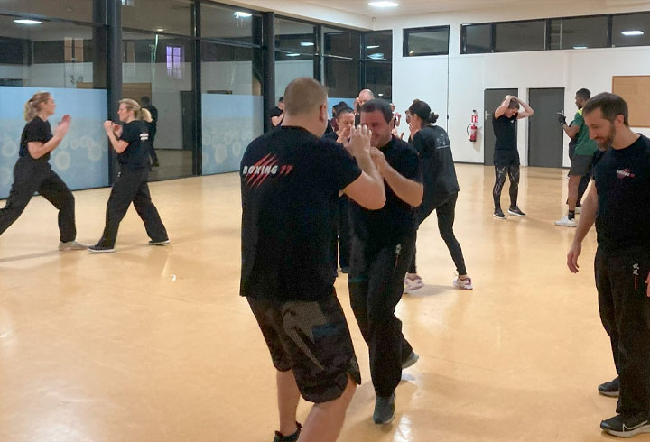 Licenciés du Dojo 77 en plein entraînement de kick-boxing, pratiquant une session de sparring pour une mise en scène de combat, sous la supervision de leur instructeur.